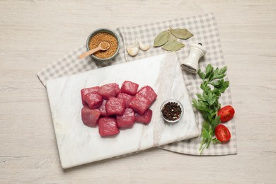 Photo of Raw beef meat and different ingredients for cooking delicious goulash on light wooden table, flat lay