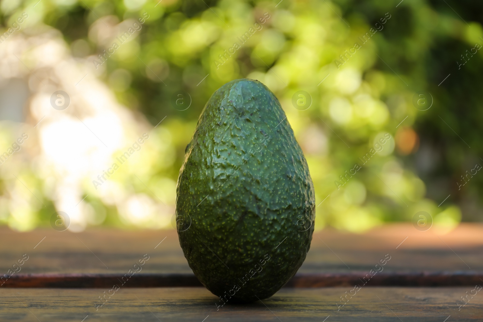 Photo of Fresh avocado on wooden table outdoors, closeup