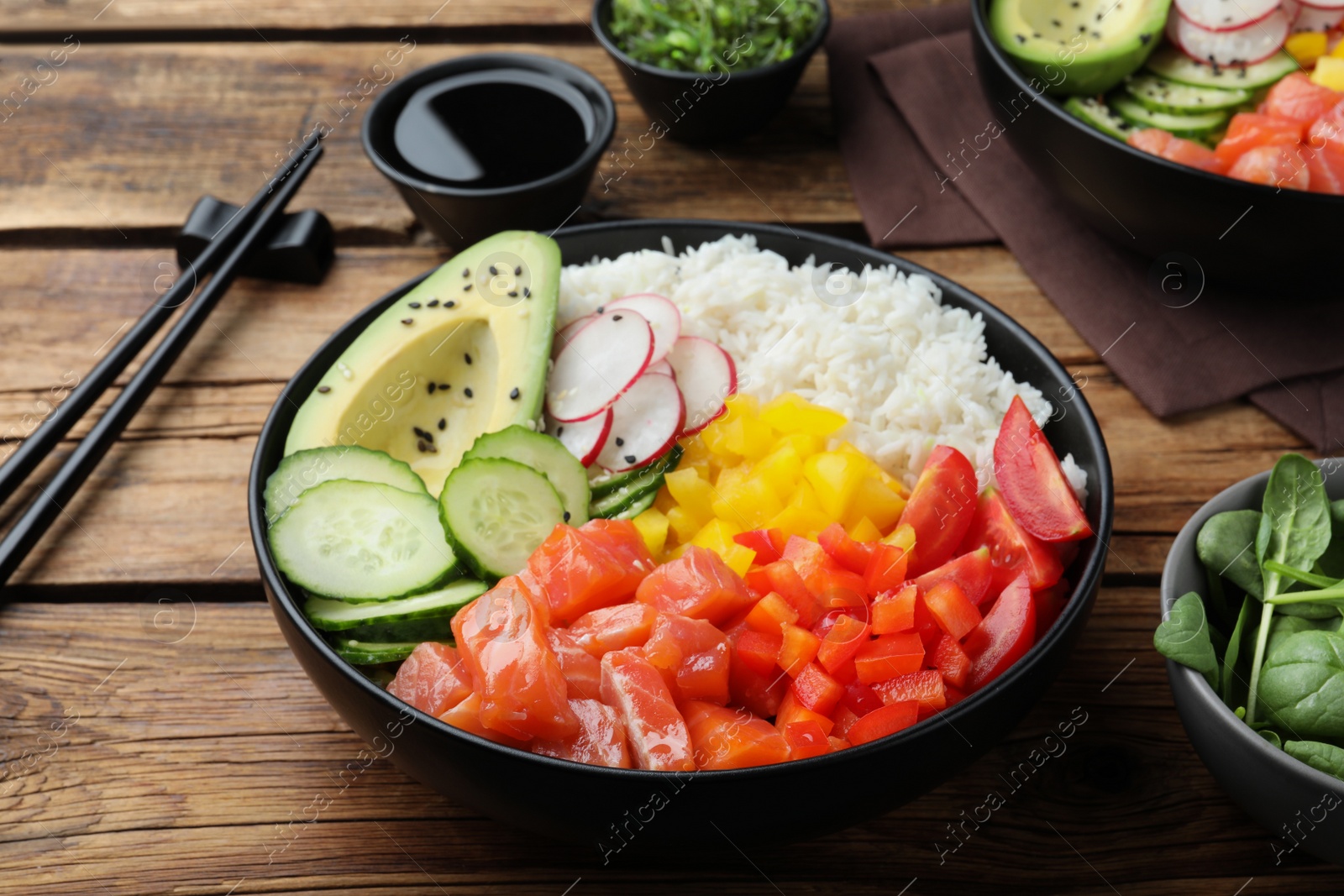 Photo of Delicious poke bowl with salmon and vegetables served on wooden table