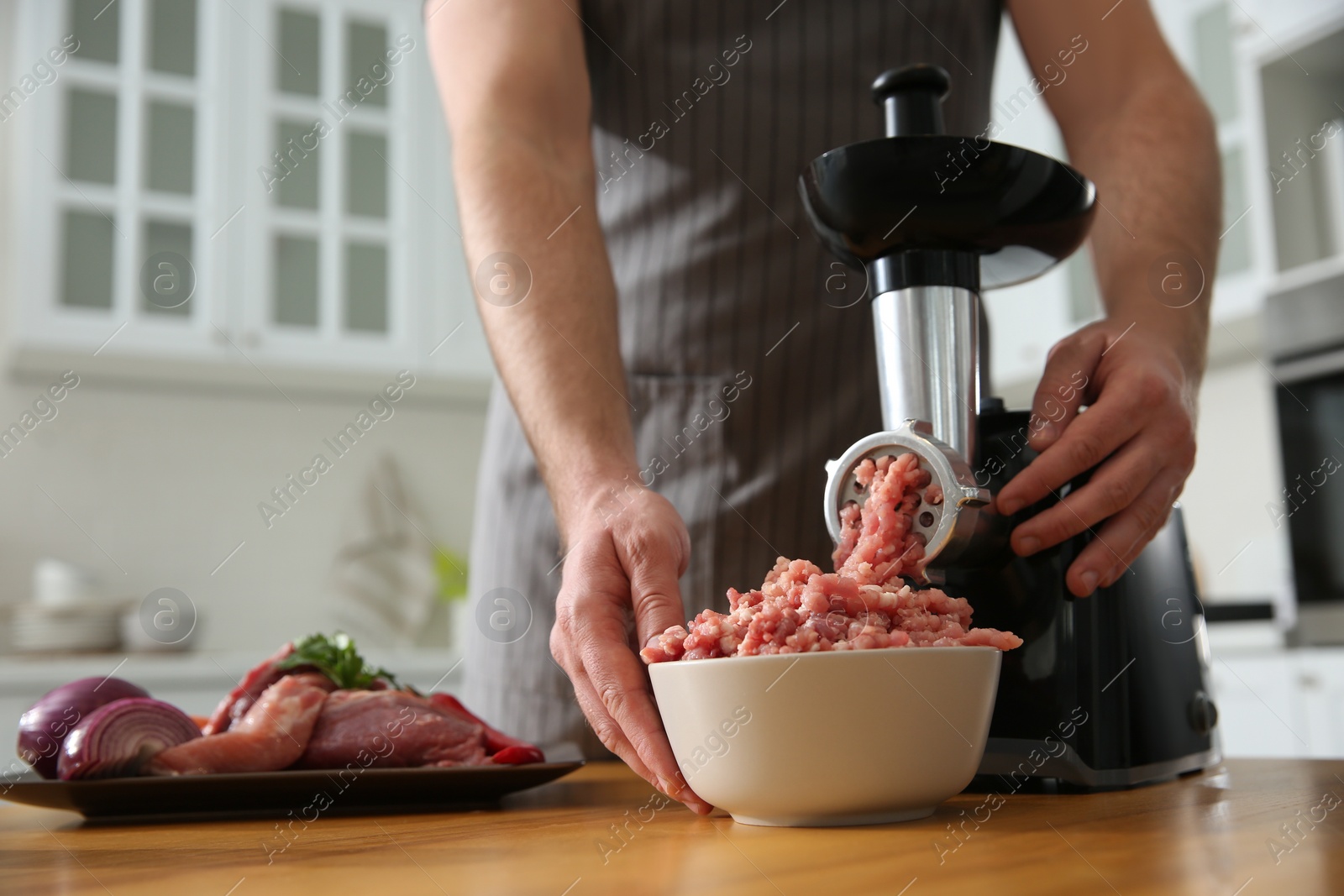 Photo of Man using modern meat grinder in kitchen, closeup