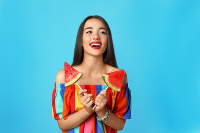 Beautiful young woman posing with watermelon on color background