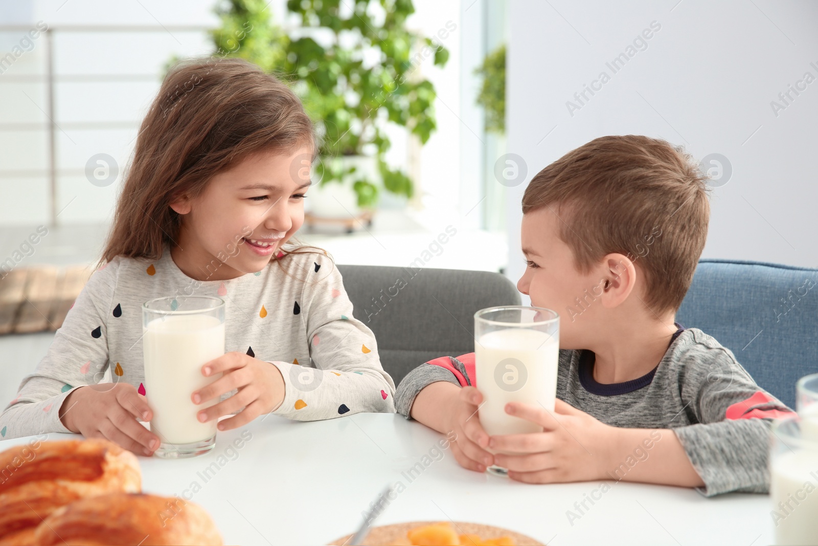 Photo of Cute little kids having breakfast with milk at table