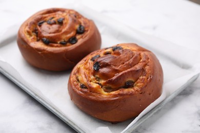 Photo of Delicious rolls with raisins on white table, closeup. Sweet buns