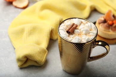 Delicious marshmallow drink and yellow sweater on light grey table