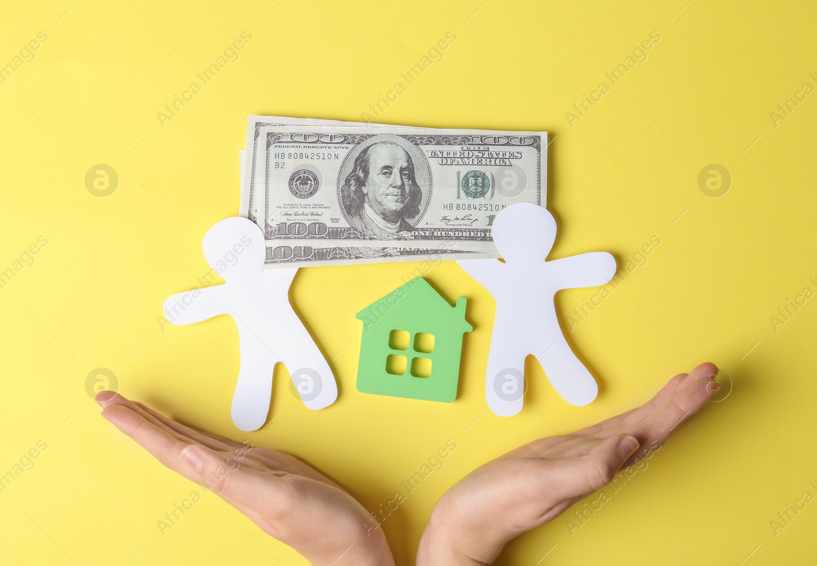 Photo of Woman holding hands near paper silhouettes of people, house and money bills on color background, top view. Life insurance concept