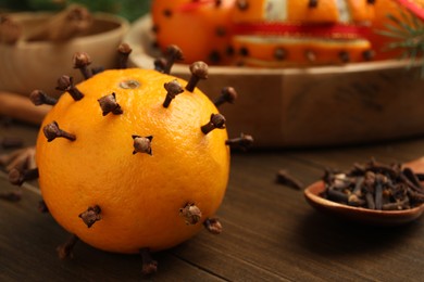 Photo of Pomander ball made of tangerine with cloves on wooden table, closeup. Space for text