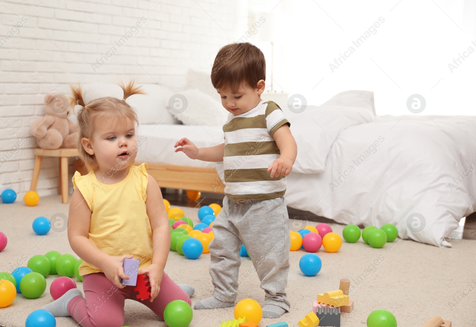 Photo of Cute little children playing with toys on floor at home