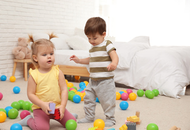 Photo of Cute little children playing with toys on floor at home