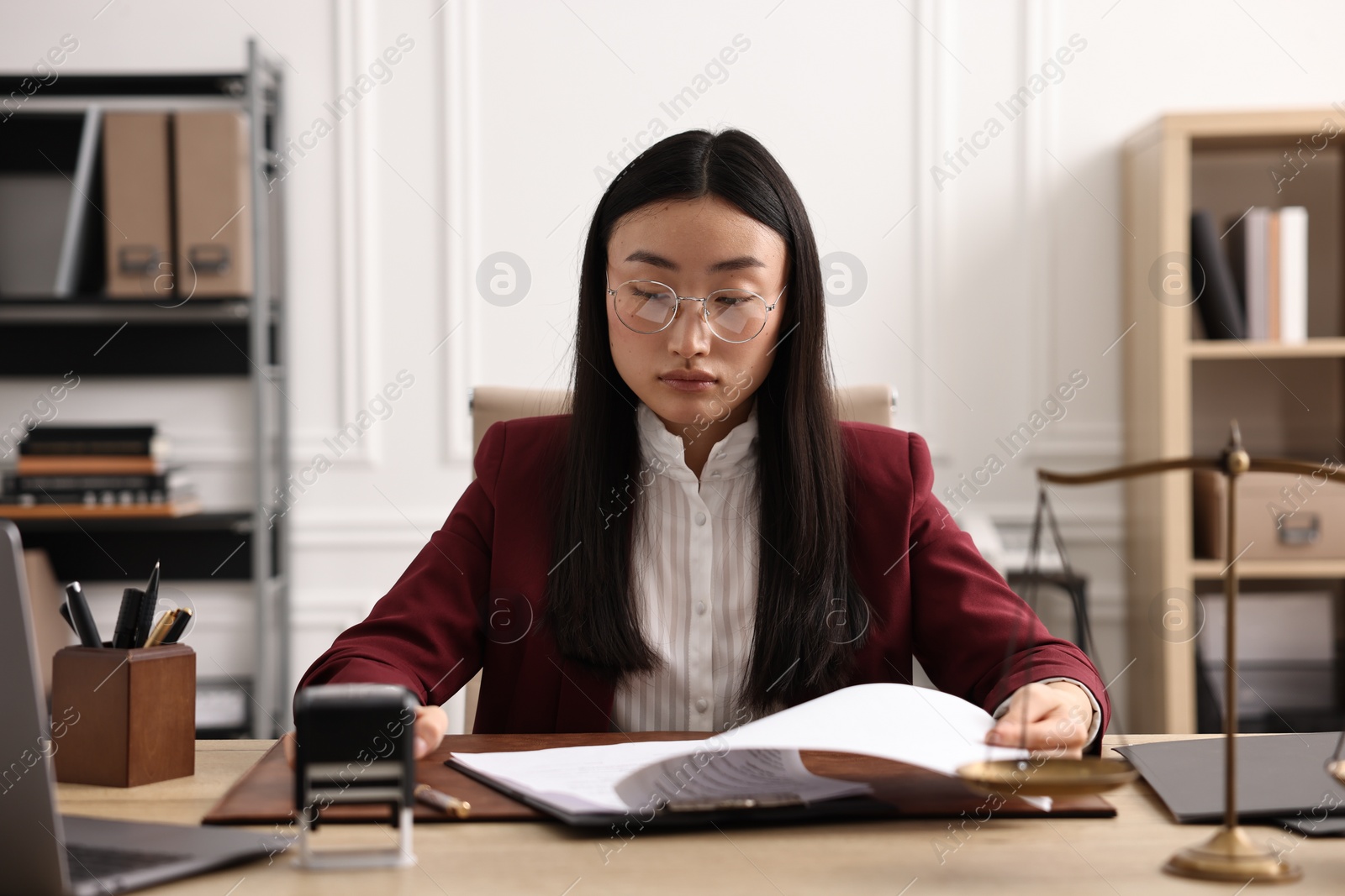 Photo of Notary reading document at table in office