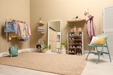 Photo of Stylish dressing room interior with trendy clothes and shoes