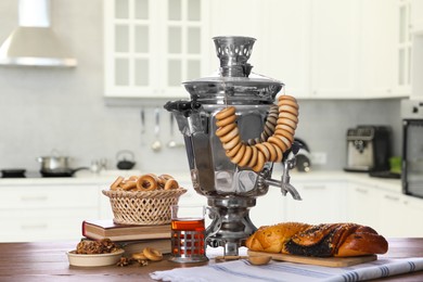 Image of Traditional Russian samovar and treats on wooden table in kitchen