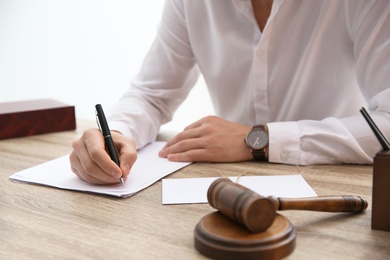 Notary working with papers and judge gavel on table in office, closeup. Law and justice concept