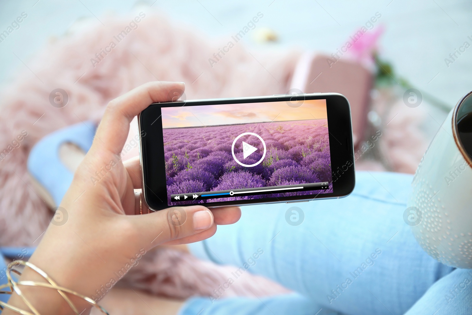 Image of Woman watching video on mobile phone while drinking coffee at home, closeup