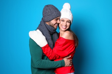 Young couple in warm clothes on color background. Christmas celebration