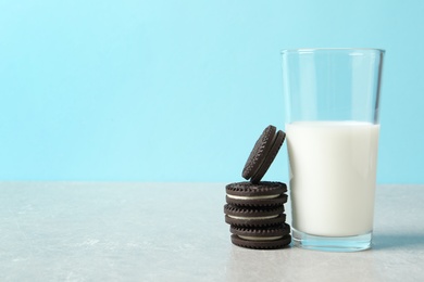Photo of Chocolate sandwich cookies and glass of milk on table against color background. Space for text