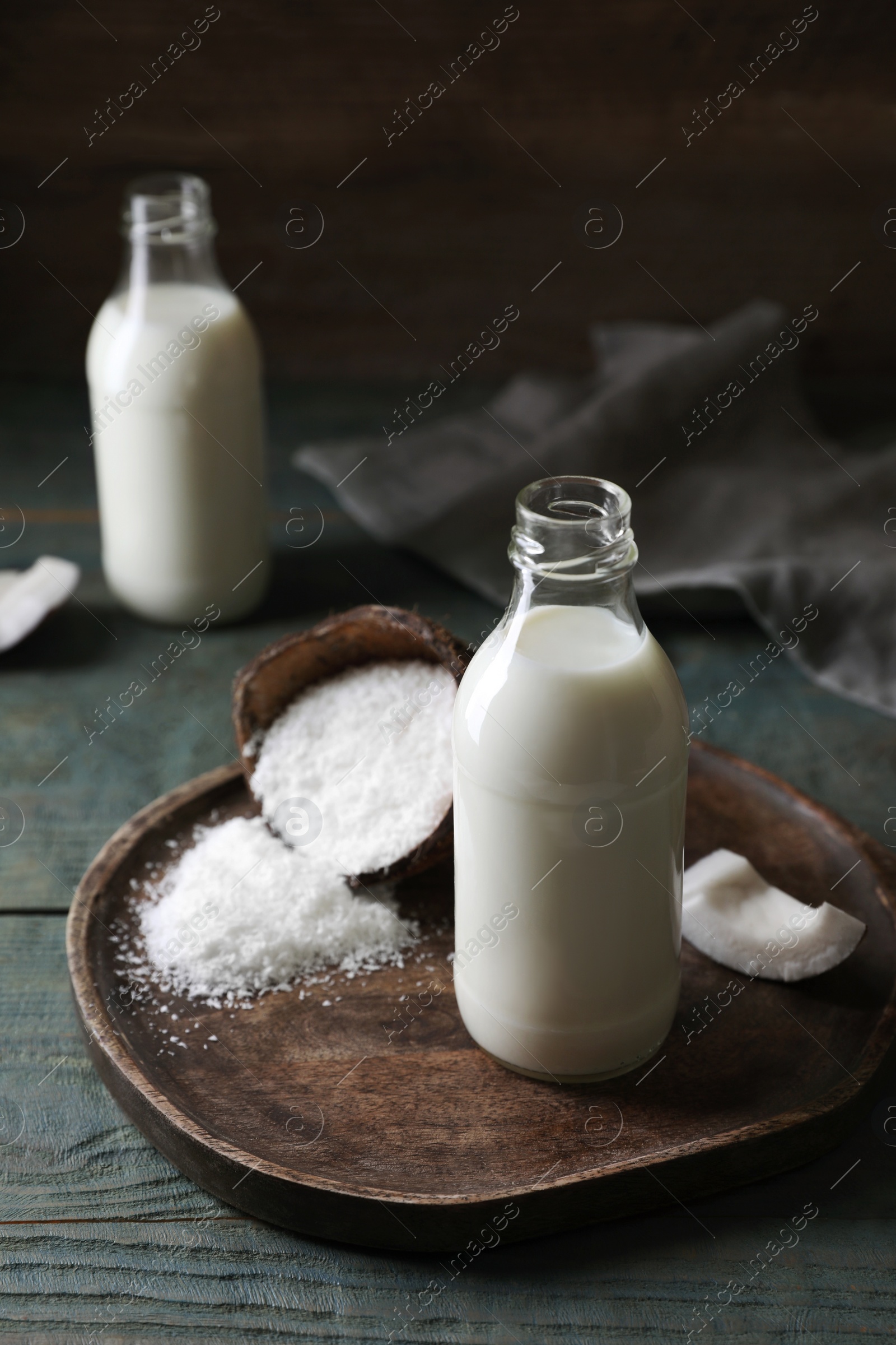 Photo of Delicious coconut milk, flakes and nut pieces on wooden table