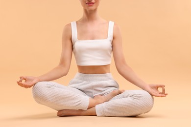 Photo of Woman practicing yoga on beige background, closeup. Lotus pose