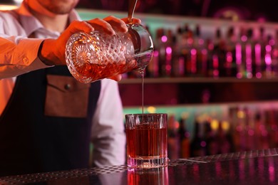 Photo of Bartender making fresh alcoholic cocktail at counter in bar, closeup. Space for text