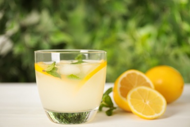 Photo of Cool freshly made lemonade in glass on white table