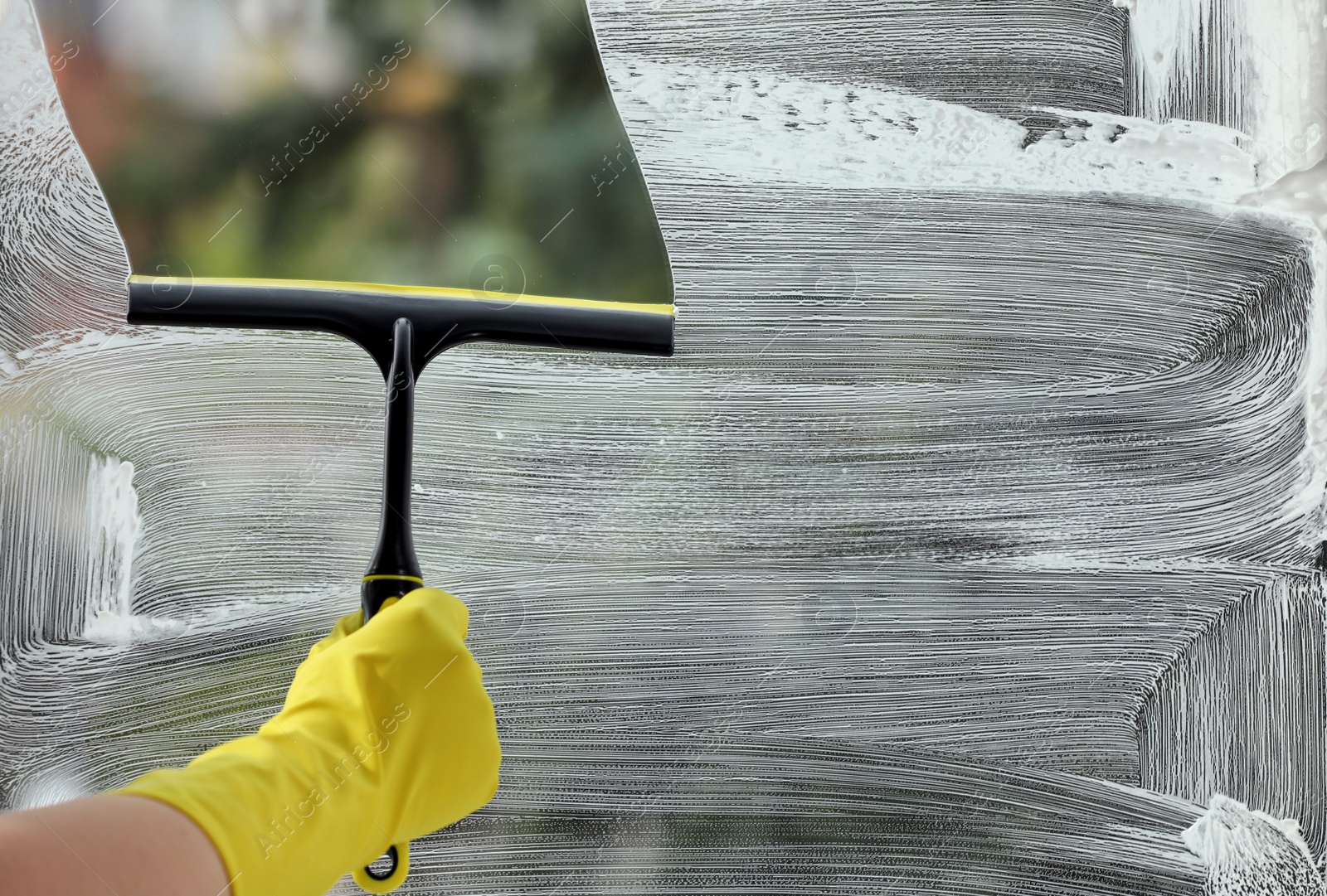 Photo of Woman cleaning glass with squeegee indoors, closeup