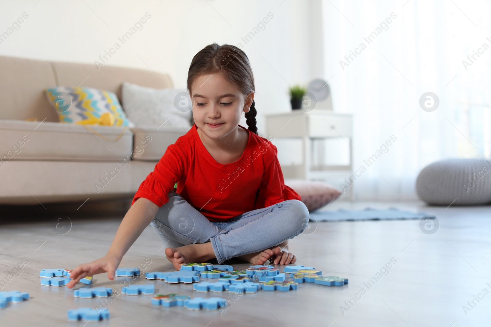 Photo of Cute little child playing with puzzles on floor indoors. Space for text