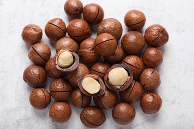 Photo of Delicious organic Macadamia nuts on white textured table, flat lay