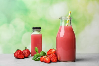 Bottles with tasty strawberry juice on table