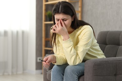 Overwhelmed woman sitting in armchair at home. Space for text