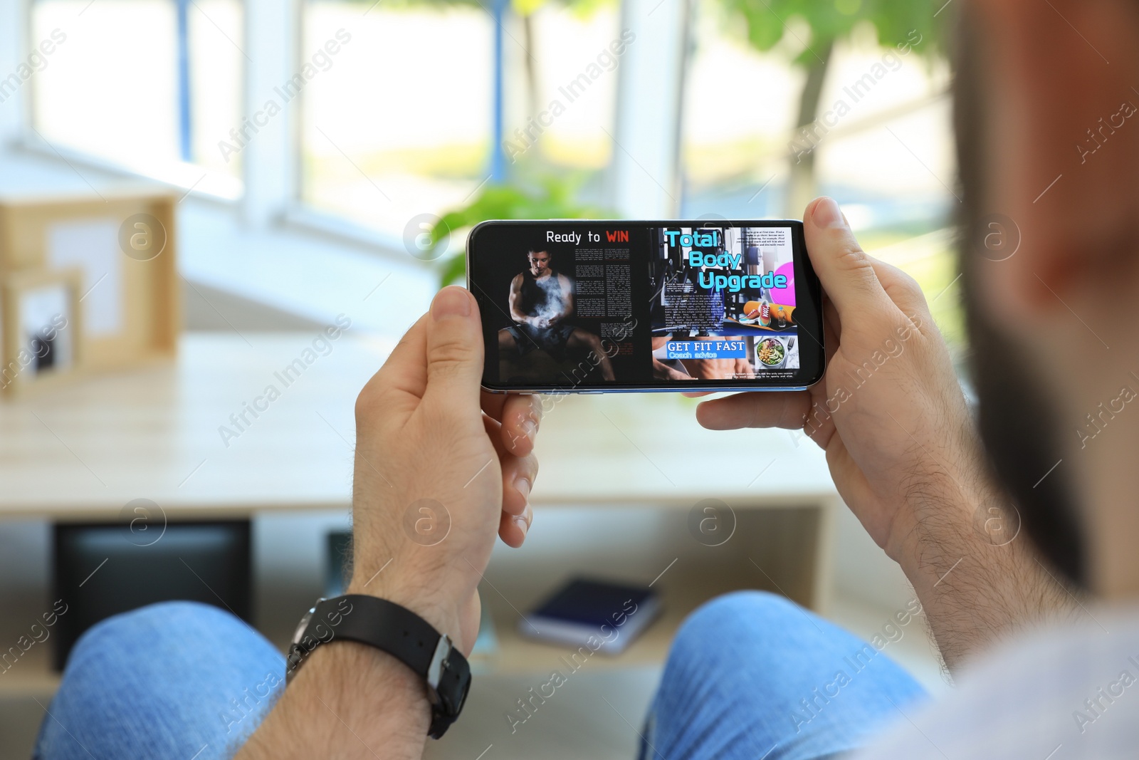 Photo of Man reading online magazine on smartphone indoors, closeup