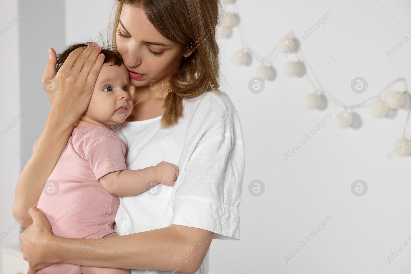 Photo of Mother hugging her cute little baby indoors, space for text