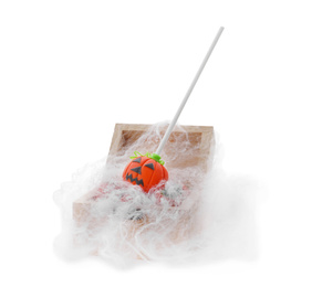 Delicious jack-o-lantern cake pop in small wooden chest with decorative cobweb on white background. Halloween season