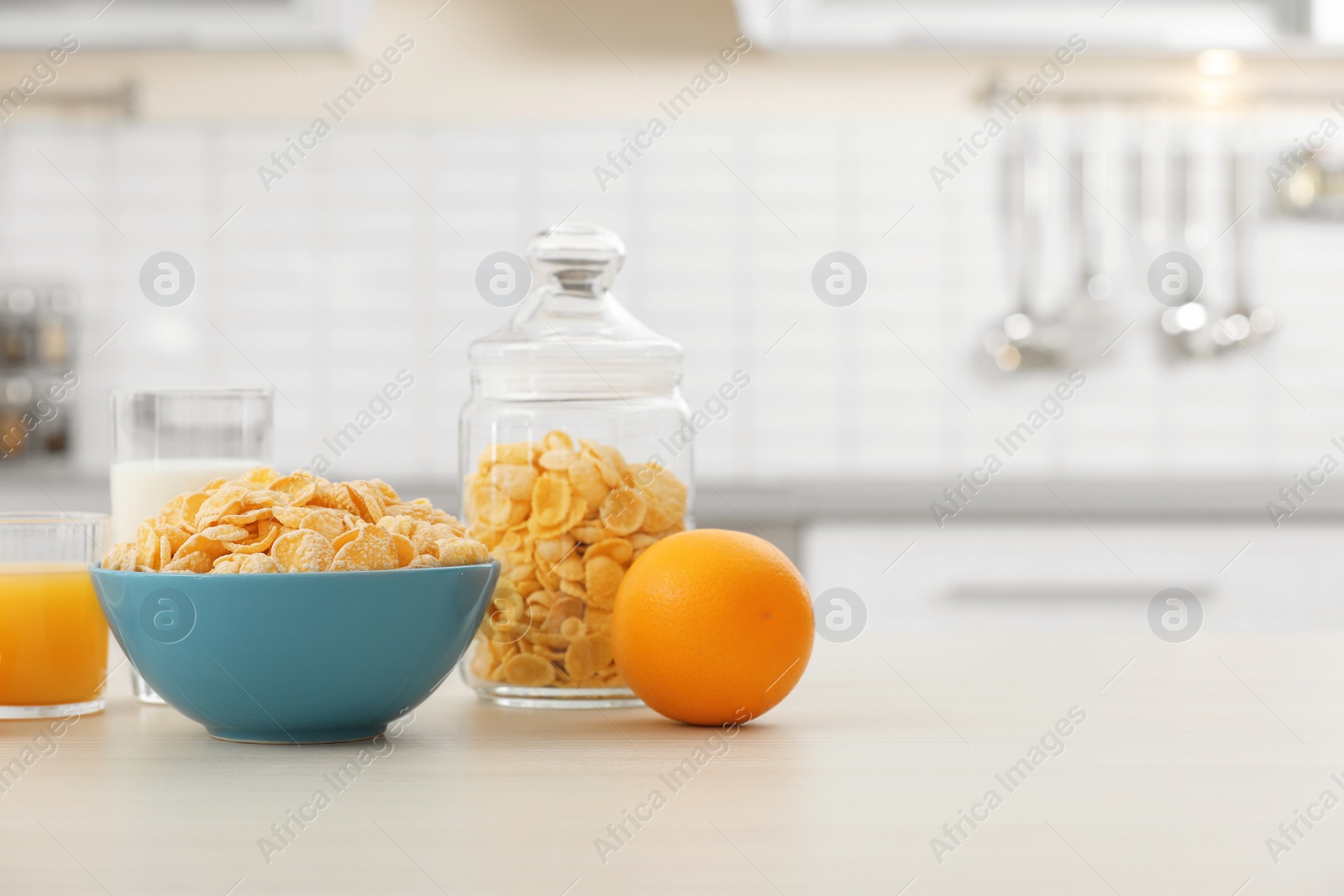 Photo of Cornflakes with glasses of juice and milk on kitchen table