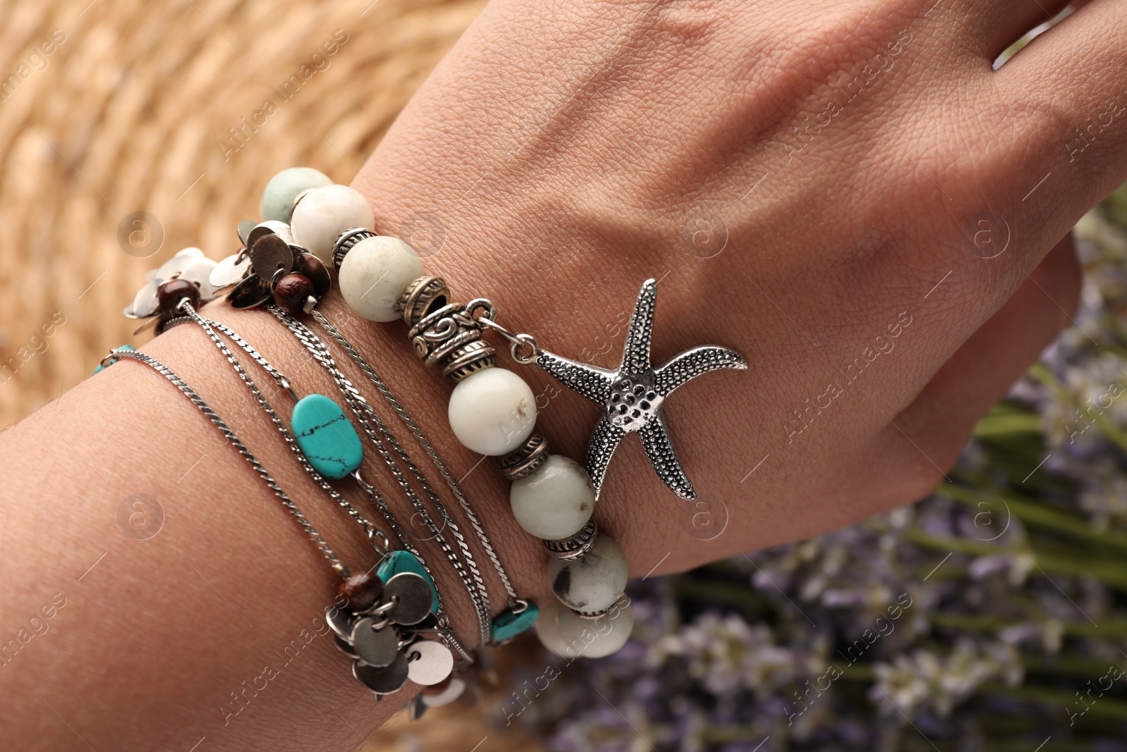 Photo of Woman wearing beautiful bracelets with gemstones on blurred background, closeup