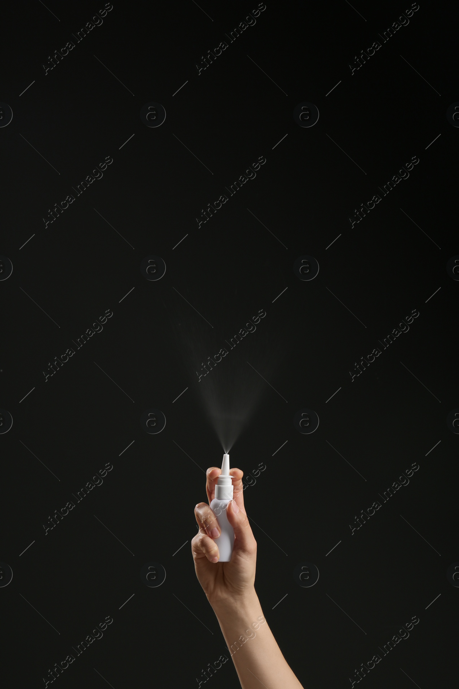 Photo of Nasal congestion. Woman spraying remedy from bottle on black background, closeup with space for text