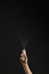 Nasal congestion. Woman spraying remedy from bottle on black background, closeup with space for text