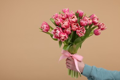 Photo of Woman holding beautiful bouquet on beige background, closeup. Space for text