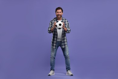 Emotional sports fan with soccer ball on purple background