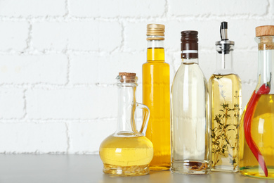 Photo of Different cooking oils on grey table. Space for text