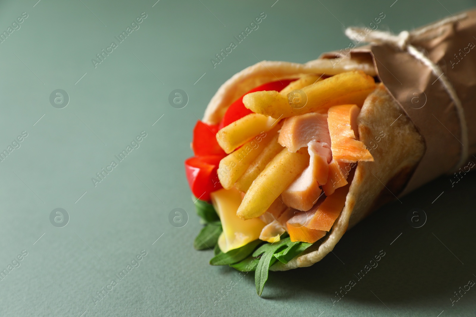 Photo of Delicious pita wrap with chicken, french fries and pepper on light blue background, closeup. Space for text