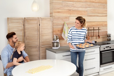 Photo of Young woman treating her family with homemade oven baked cookies in kitchen