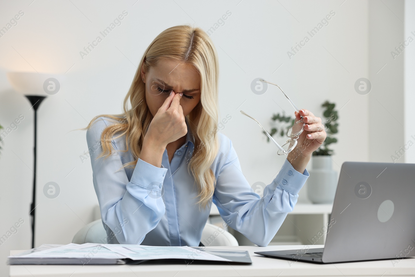 Photo of Overwhelmed woman with glasses at table in office