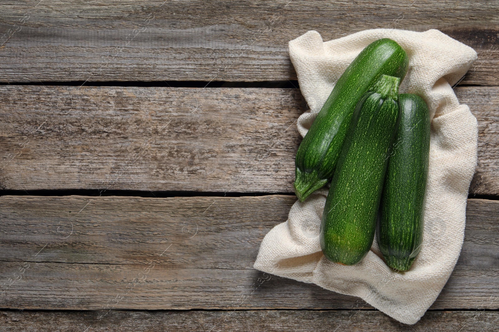 Photo of Raw ripe zucchinis on wooden table, flat lay. Space for text