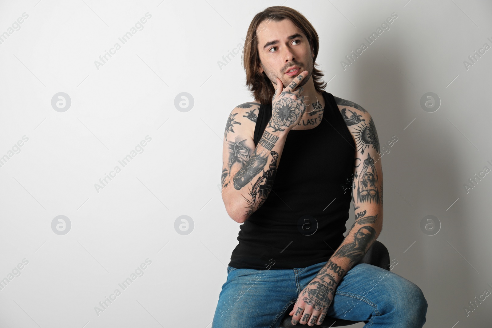 Photo of Young man with tattoos on body against white background