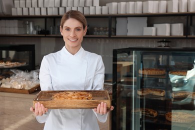 Photo of Professional baker with freshly baked pastry in store. Space for text