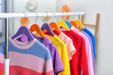 Photo of Colorful children's clothes hanging on wardrobe rack indoors, closeup
