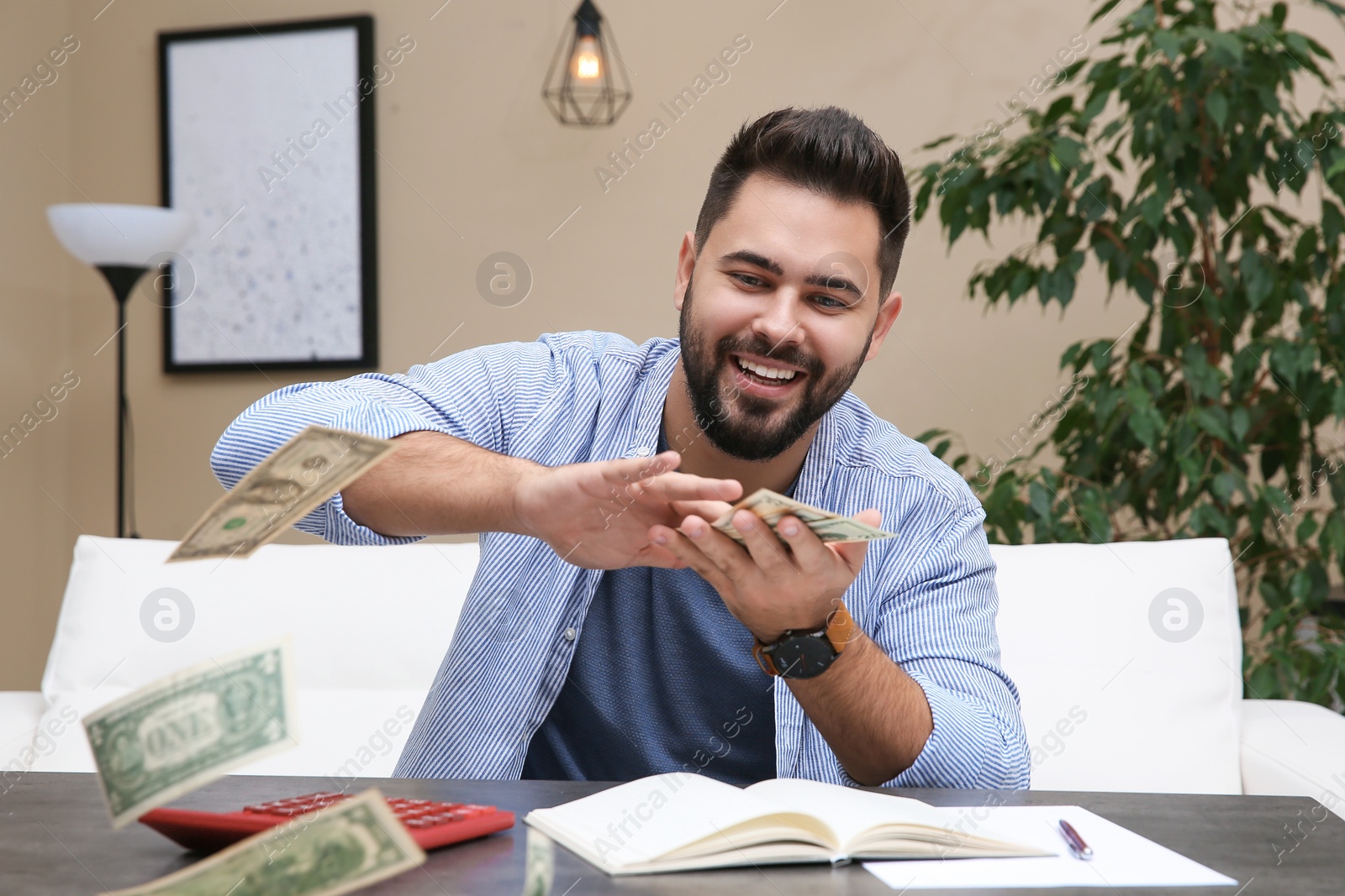 Photo of Young man throwing money at table indoors