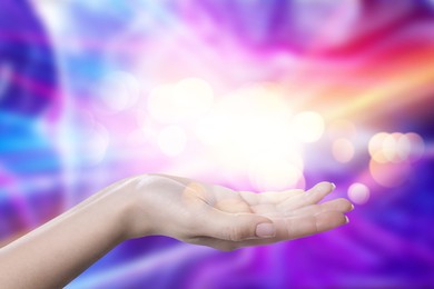 Image of Aura phenomena. Woman with lights of energy coming out from her hand against color background, closeup
