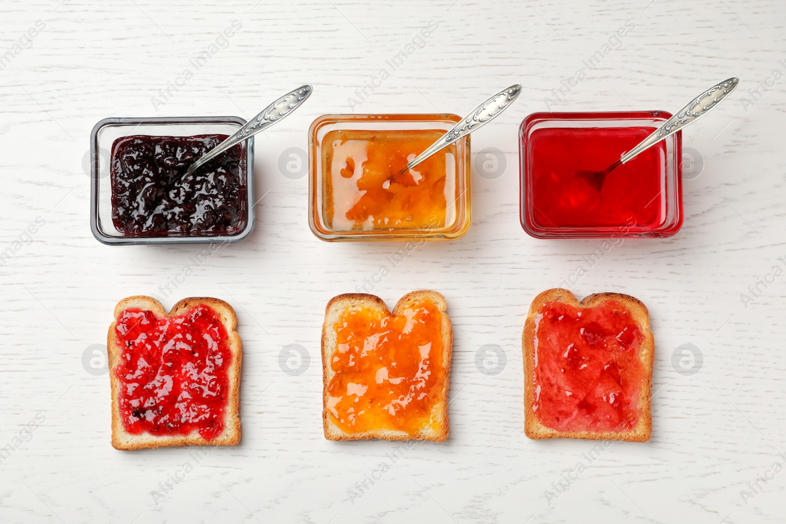 Photo of Toasts with various jams on wooden table, flat lay