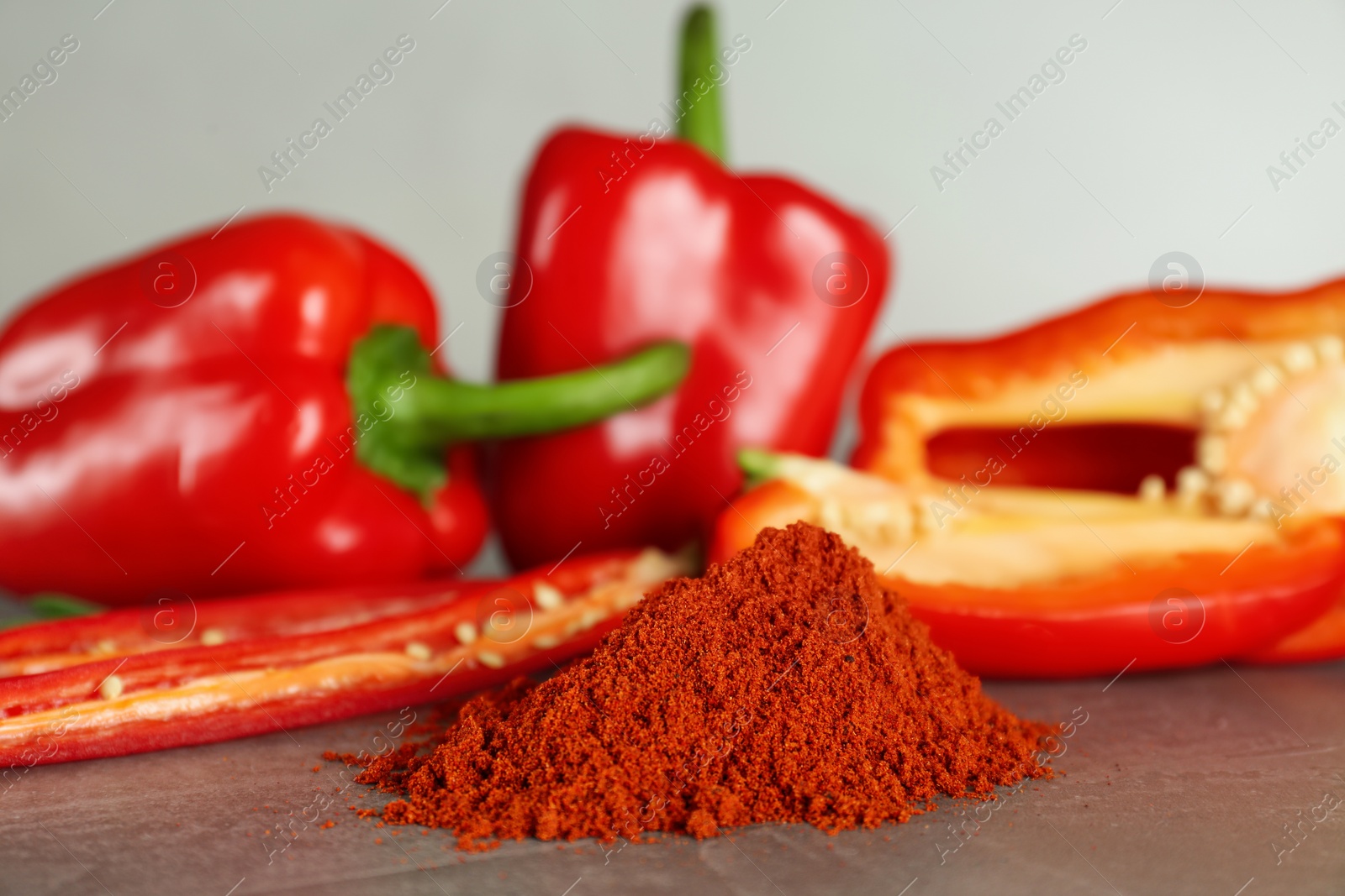 Photo of Fresh chili and bell peppers with paprika powder on grey table, closeup