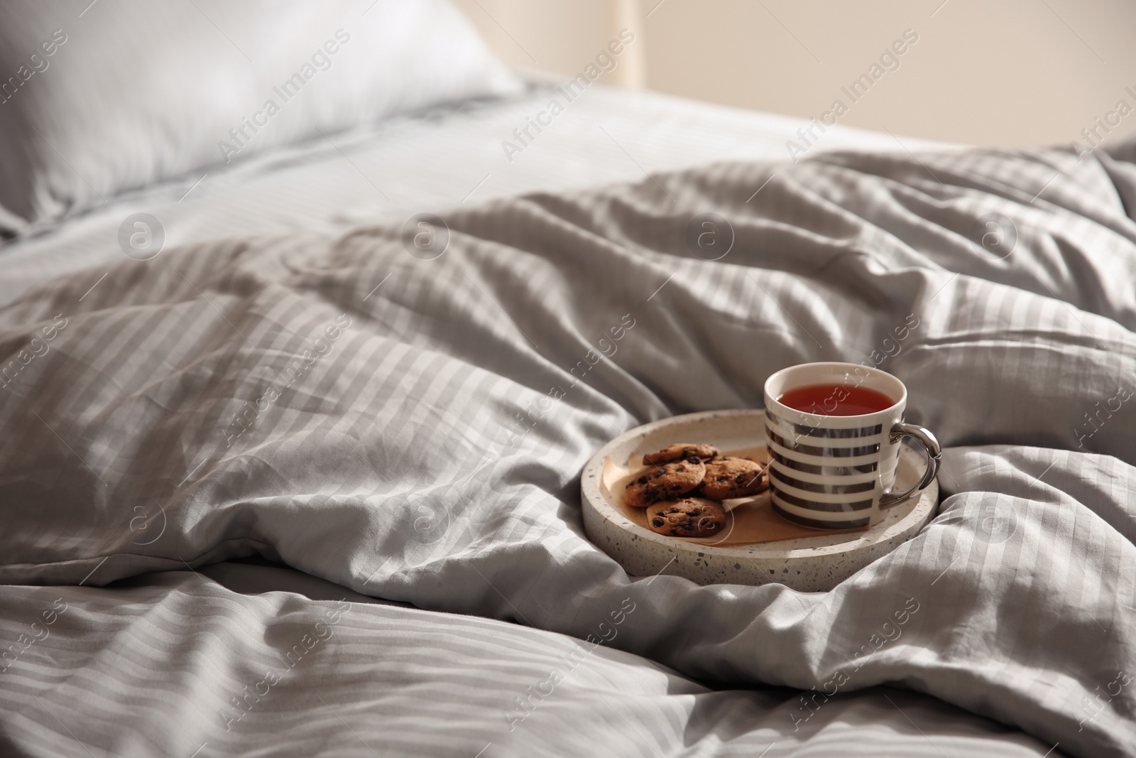 Photo of Tray with cup of tea and cookies on soft blanket. Space for text